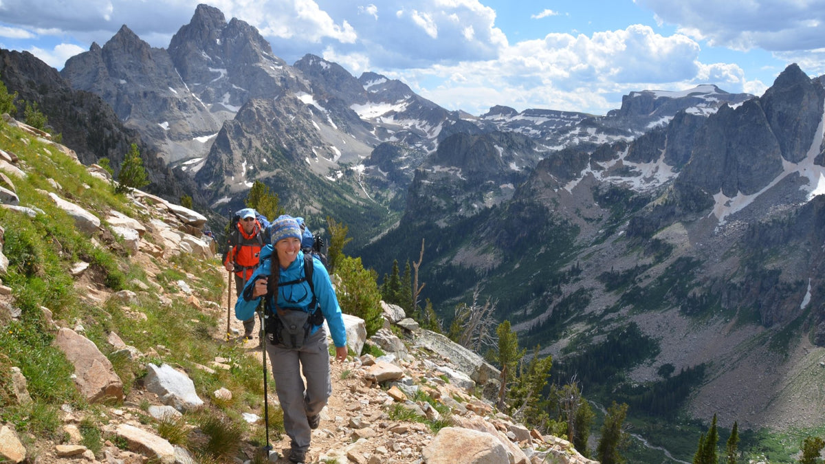 Two backpackers on trail with Grand Teton rising behind them, Grand Teton National Park, Wyoming