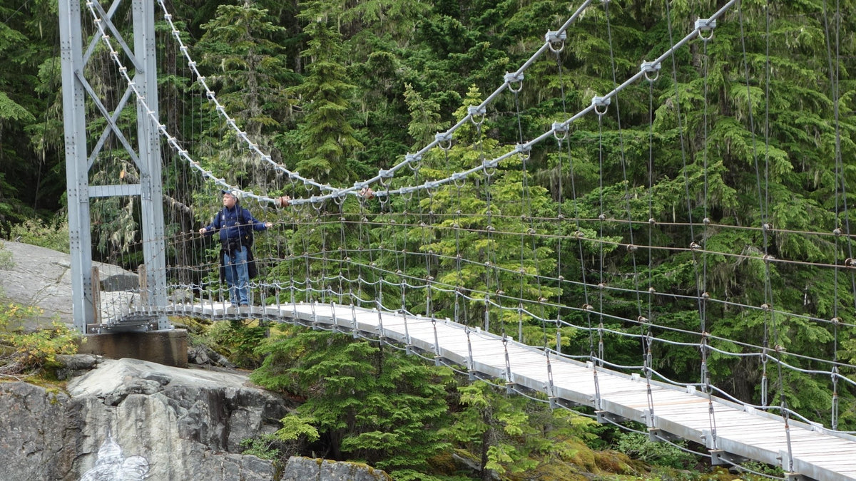 A hiker crosses a suspension bridge on the Wonderland Trail, Mount Rainier National Park, Washington