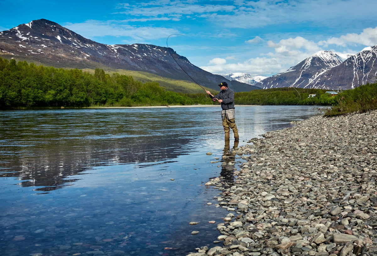 Fly fisherman wading and reading the current on a wide river