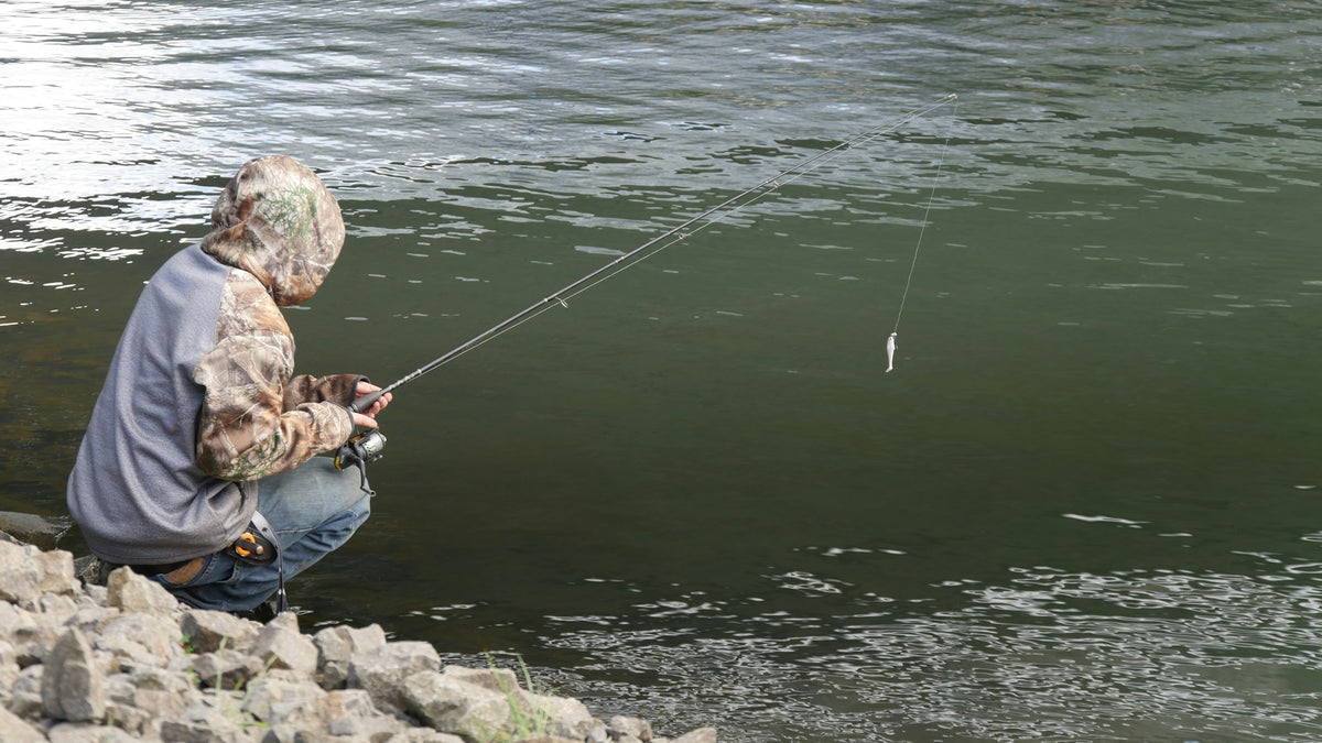 Angler fishing a cold, clear mountain river at dusk